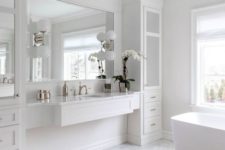 a chic and stylish white bathroom with marble hex tiles on the floor, a tub, a vanity with storage units and a mirror