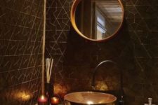 a chic black and gold bathroom with geometric tiles, gold accents and a gold frame mirror plus a unique sink