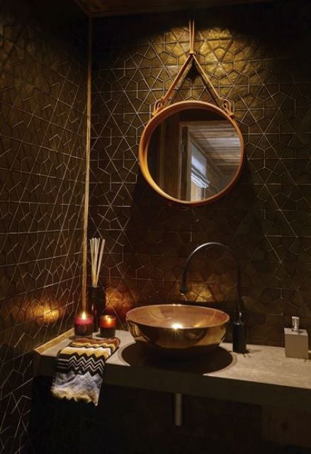 a chic black and gold bathroom with geometric tiles, gold accents and a gold frame mirror plus a unique sink