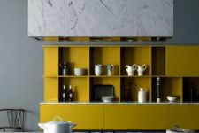 a chic minimalist kitchen with a black kitchen island, mustard cabinetry, white marble touches looks fantastic