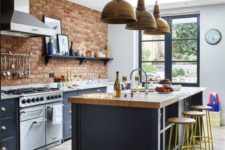 a chic navy kitchen with a brick wall, wooden countertops and metal lamps over the table for a bold look