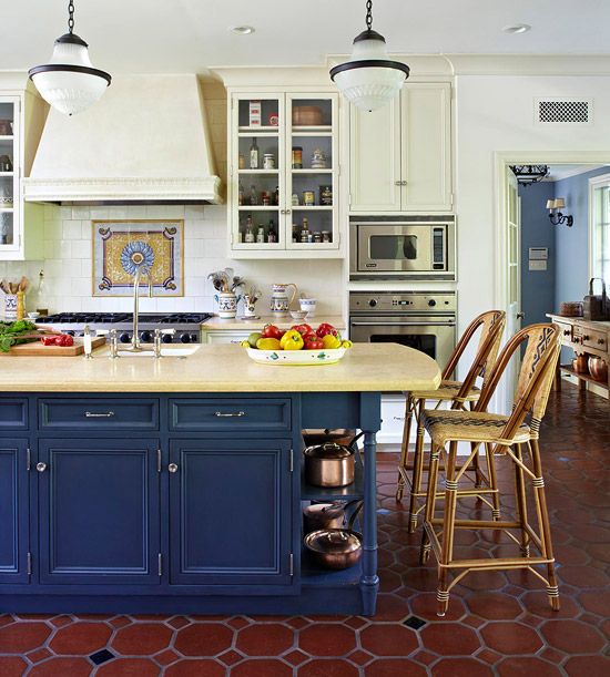 a chic traditional kitchen with light yellow walls, cabinets and a navy kitchen island plus tiles on the floor