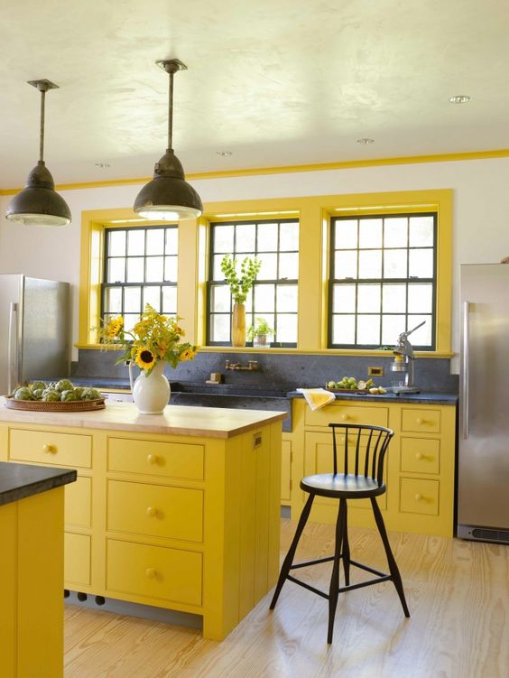 a chic vintage yellow kitchen with a navy blue backsplash and countertop plus black pendant lamps