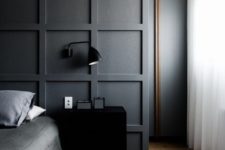 a contemporary mmoody bedroom with a statement graphite grey paneled wall that separates the sleeping space from the closet
