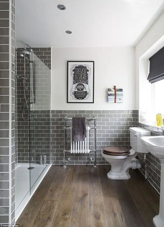 a cool modern bathroom with grey subway tiles, a stained floor, white vintage appliances and cool decor