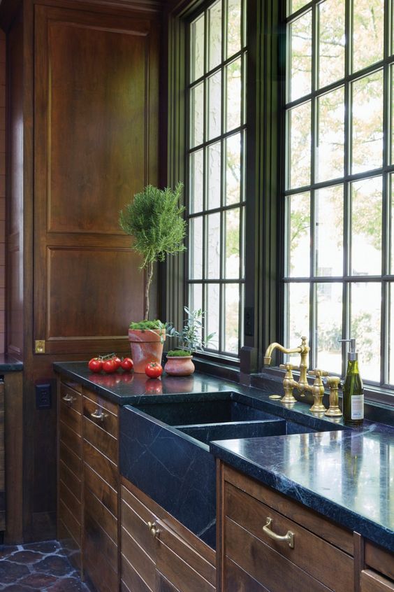 A gorgeous brown kitchen of natural wood and blue stone countertops and a built in sink for a refined feel