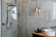 a gorgeous minimalist grey bathroom with large scale tiles, a pendant lamp and a floating vanity with a sink
