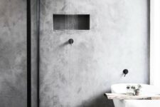 a grey minimalist bathroom done with concrete, with black fixtures and a wooden cuddy on the bathtub