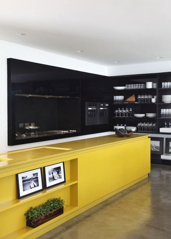 a large contemporary kitchen done with black cabinetry and walls plus a bright yellow kitchen island for a contrast