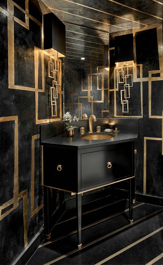 a luxurious black and gold bathroom with a geometric vanity, gold geometric detailing and gold fixtures and candles