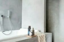a minimalist bathroom all clad with concrete, a bathtub clad with concrete and a black tile floor is a stylish idea