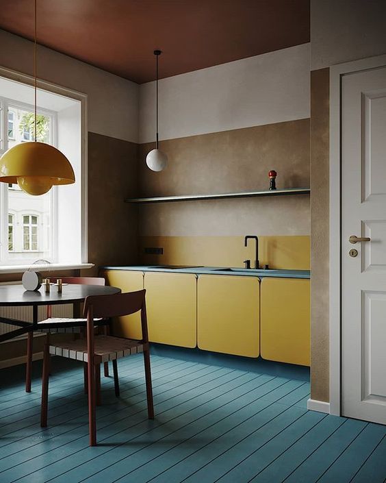 A minimalist blue and yellow kitchen with mid century modern lamps and MDF cabinets plus a cognac ceiling