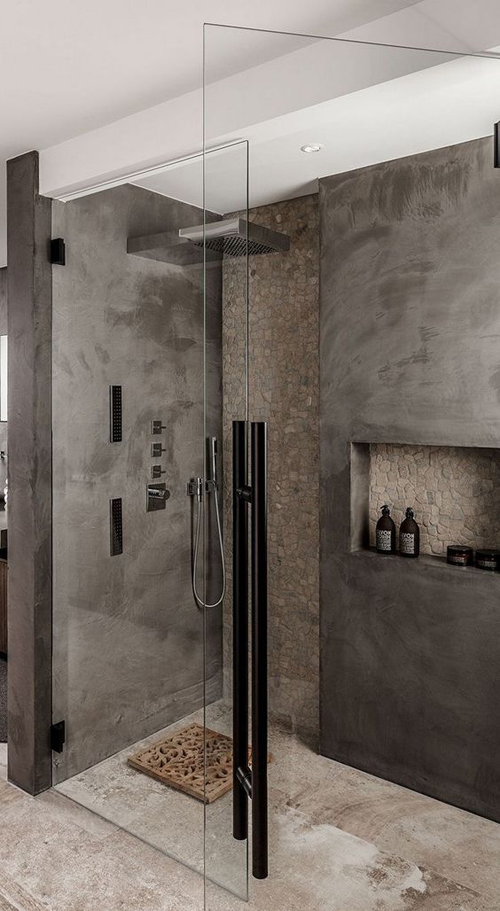 a minimalist grey and taupe bathroom done with concrete and stone, with a wooden rug and black touches