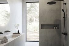 a minimalist grey bathroom clad with tiles and concrete, with a white concrete vanity and sink and black fixtures