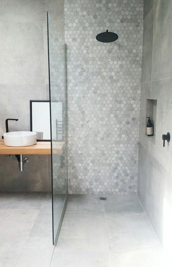 a minimalist grey bathroom done with hex and usual tiles, with a floating vanity and black fixtures