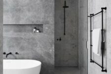 a minimalist grey marble bathroom with darker and lighter tiles, a free-standign tub and black fixtures for a more contemporary look