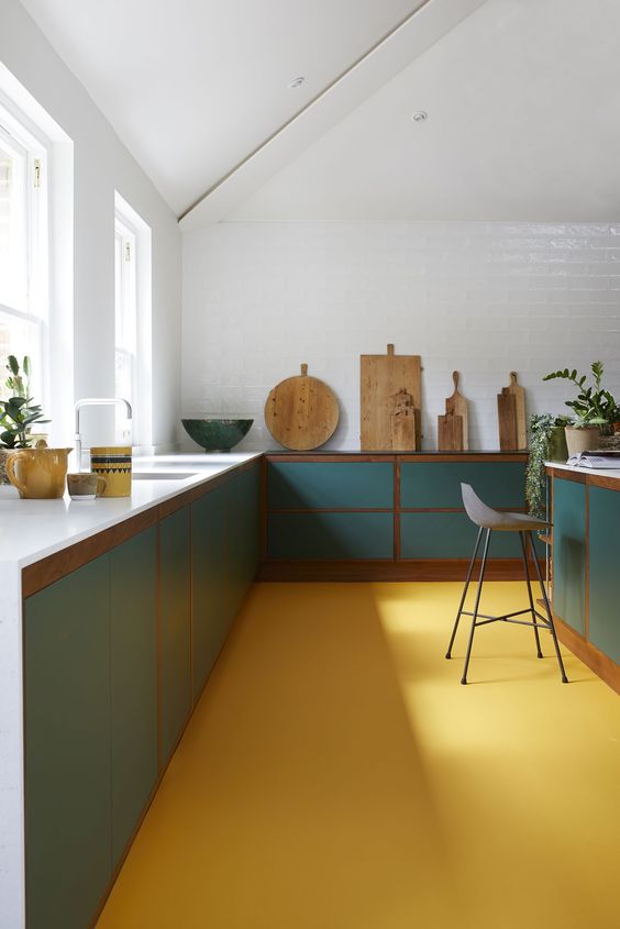 a minimalist kitchen done with a sunny yellow floor, turquoise cabinets, touches of stained wood and all white walls and ceiling
