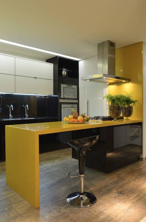 a minimalist kitchen in bold yellow and black, with glossy surfaces and lots of lights here and there
