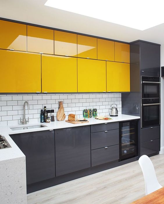 a minimalist kitchen with black lower cabinets and bright yellow upper ones plus white countertops is ultimately bold