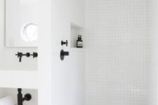a minimalist white bathroom clad with tiles in the shower space, with black fixtures and all white everything