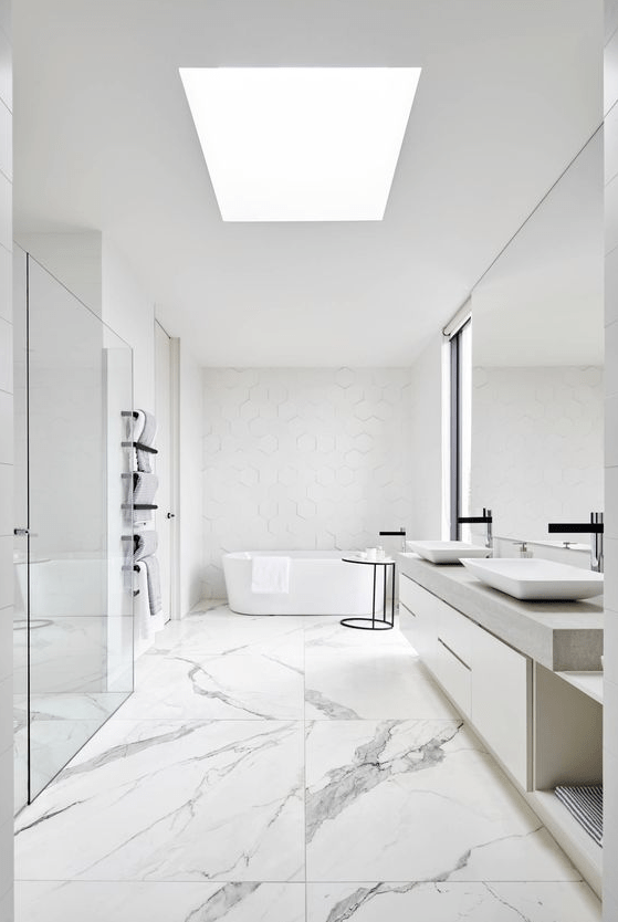 a neutral minimalist bathroom with catchy tiles of various sizes, a skylight, a large mirror and vanity, a tub and a shower space