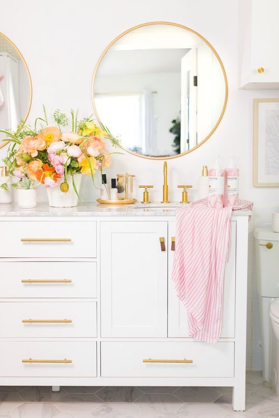 a pretty white bathroom with gold handles, gold framed mirrors and fixtures looks dreamy and very romantic