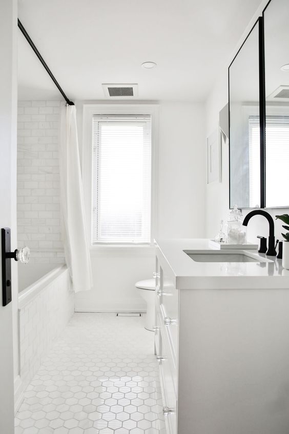 a simple white bathroom done with marble subway tiles and hex ones plus a white vanity and a window for some natural light
