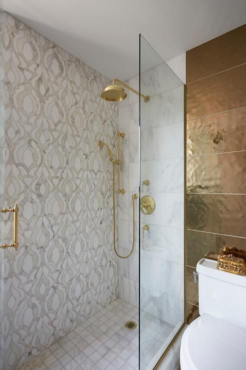 a small bathroom with neutral printed tiles, gold fixtures, a dark gold tile wall and more accents looks wow