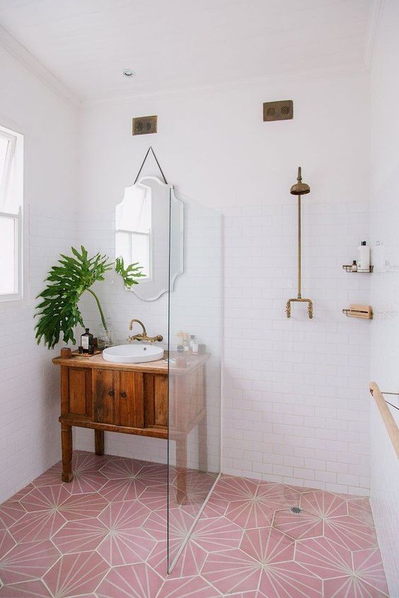 a small contemporary bathroom with a pink tile floor and brass and pink touches and fixtures for a bold look