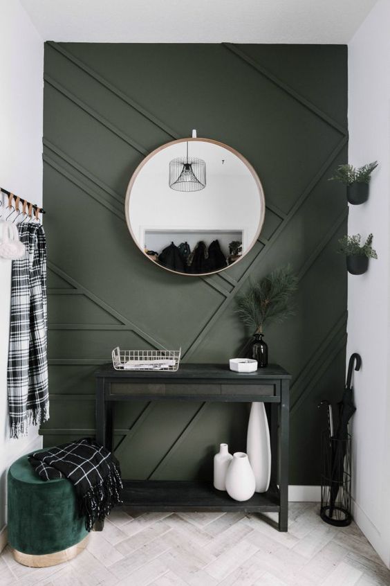 a small modern entryway with a statement graphite grey paneled wall and a matching ottoman for a chic look