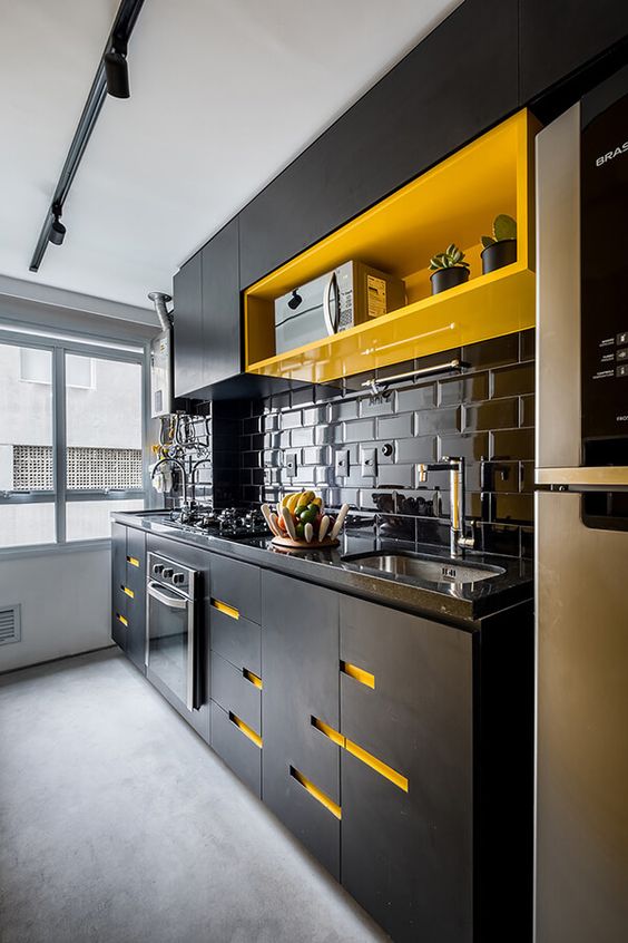 a statement black kitchen with a bright yellow shelf and yellow cutouts on the cabinets plus a glossy tile backsplash