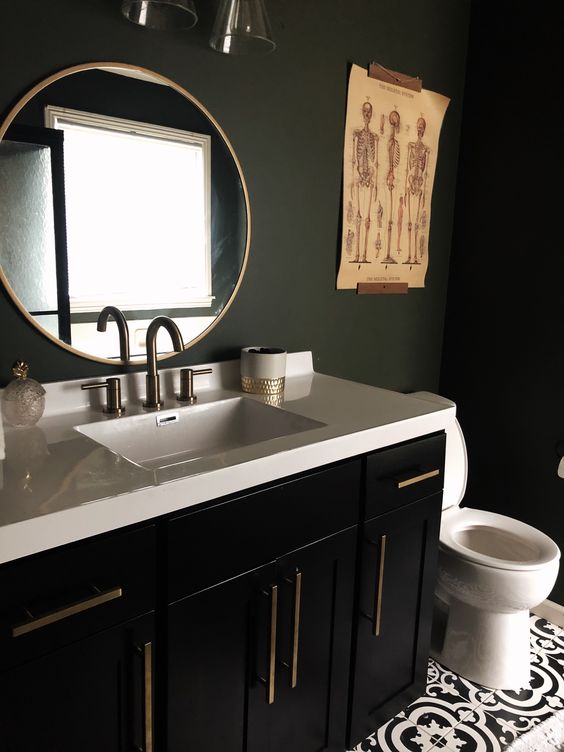 a stylish and moody bathroom with matte black walls, a black vanity, a white stone countertop and catchy artworks
