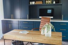 a stylish home office with a navy storage unit, a catchy industrial desk of wood and metal, a leather chair and a wicker basket