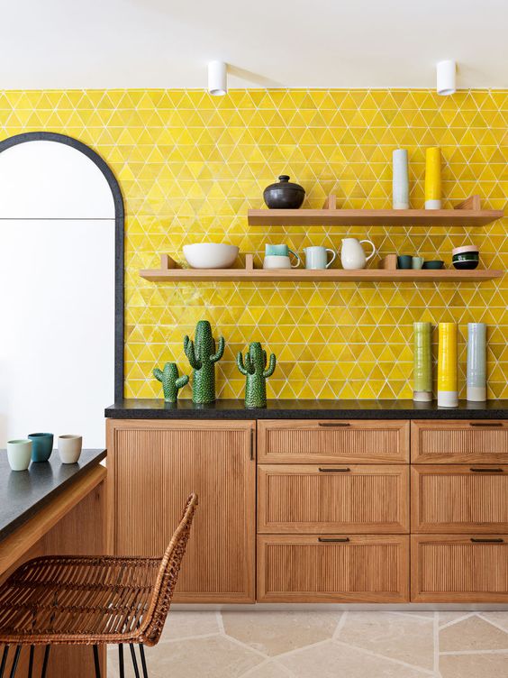 a stylish mid-century modern kitchen with wooden cabinets and furniture, black countertops and a lemon yellow tile backsplash