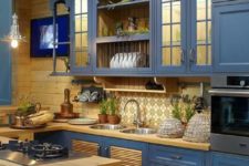 a stylish vintage farmhouse kitchen with blue cabinets and buttercream yellow wooden countertops and backsplashes