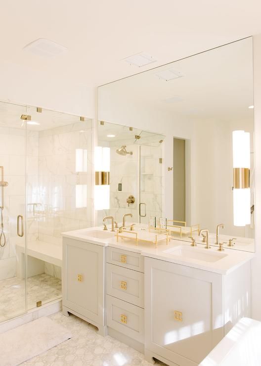 a super elegant white bathroom with chic gold fixtures, handles, knobs and other accents looks very chic