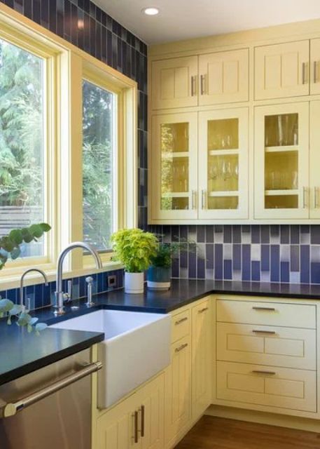 a traditional yellow and navy kitchen with navy and white tiles on the wall and backsplash