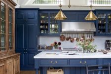 a vintage blue kitchen with white marble countertops and a backsplash, with light borwn floors and a buffet plus touches of gold