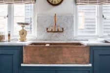 a vintage navy kitchen with a built-in copper hammered sink and a matching faucet to make up a bold look