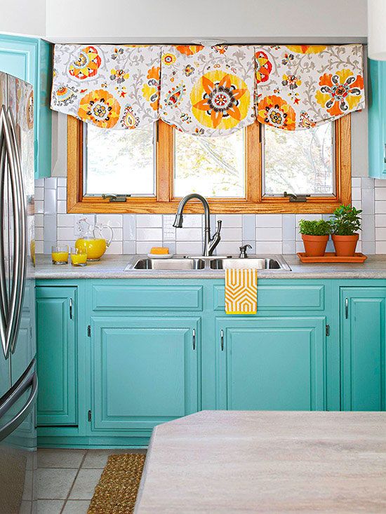a vintage turquoise kitchen with a white tile backsplash, a bright pritned curtain and a white stone countertop