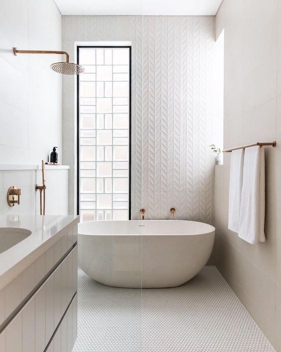 a white bathroom done with various types of tiles, an oval tub, two windows for light and a floating vanity