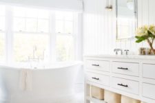 a white bathroom with shiplap walls, white marble tiles on the floor and a tub by the window looks very airy