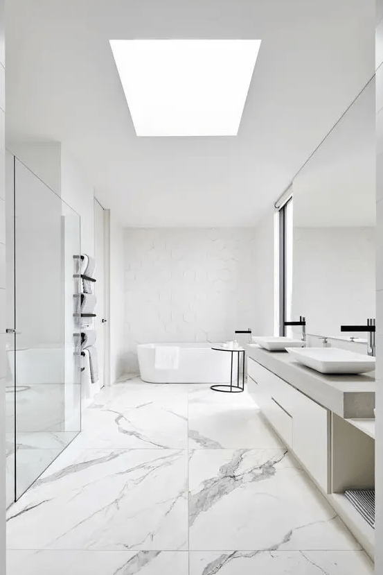 a white minimalist bathroom with catchy tiles of various sizes, a skylight, a large mirror and vanity, a tub and a shower space