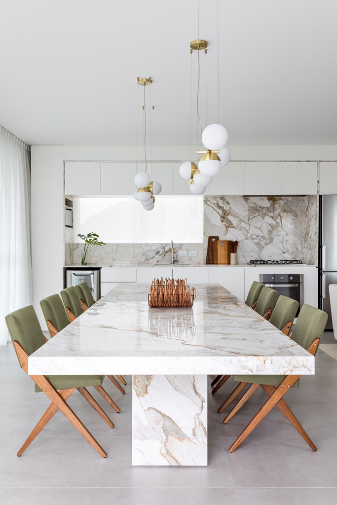 The kitchen is done with minimalist white cabinets, a marble backsplash, the dining space is next to it echoing the design with a fabulous marble dining table