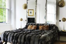 03 a modern luxurious bedroom with a vintage mirror as a headboard, a faux fur bedspread and some touches of gold