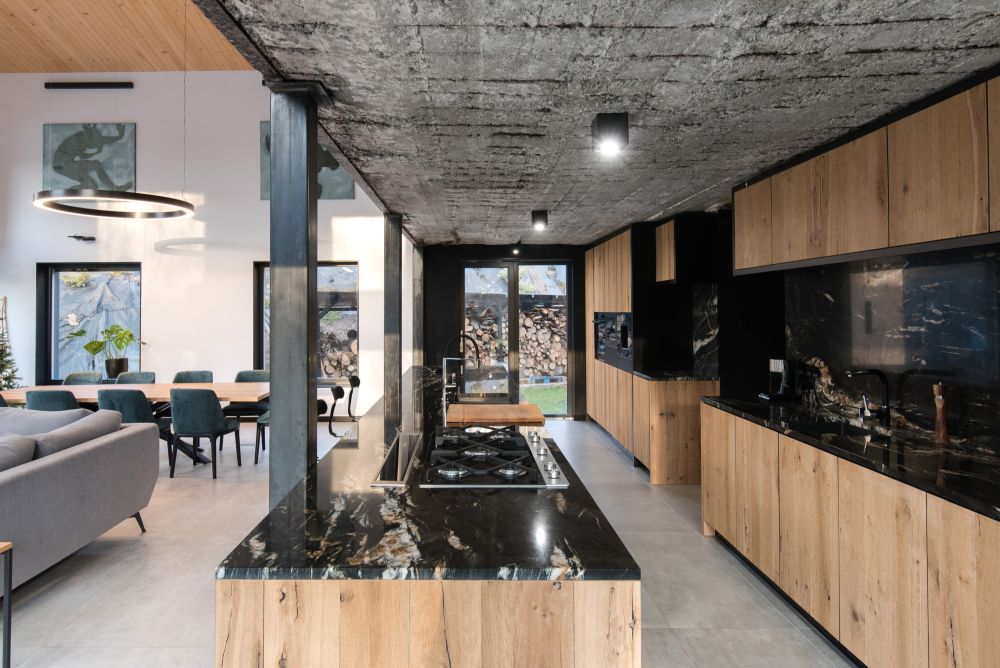 The kitchen is large, it's done in neutral stained wood and black stone plus a concrete ceiling