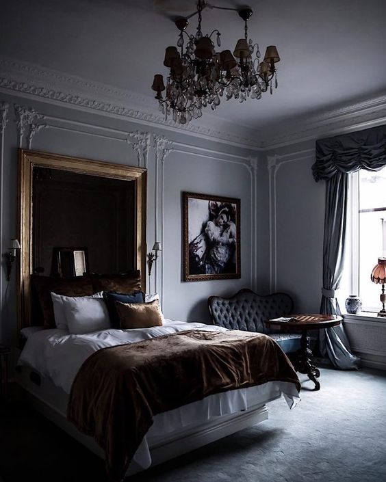 A refined moody bedroom with a statement mirror in a simple frame and a chic chandelier that make the space wow