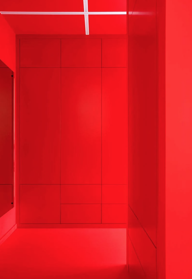 The entryway is bright red, with sleek storage units and a large mirror and built in lights