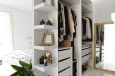 05 a small open closet in white with shelves, holders and drawers doubles as a space divider