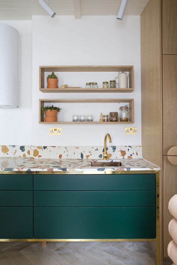 hunter green kitchen cabinets accented with gold touches and with bright terrazzo countertops are very chic and bold